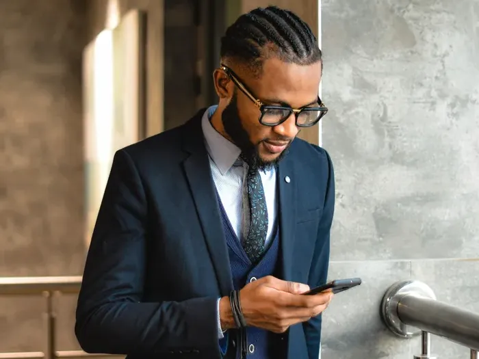 Confident businessman in suit checking his phone at work, representing service professionals on Town Service Connect
